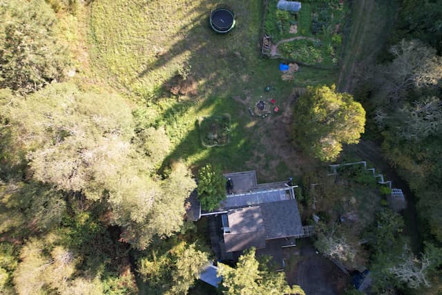 An aerial view of a house with garden shaded by trees, showing where the shadows lie.